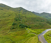 Luftaufnahme eines majestätischen Wasserfalls, der in einen gewundenen Fluss stürzt, umgeben von üppig grünen Bergen, Kyle, Schottland, Vereinigtes Königreich