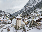 Aerial view of picturesque snowy village with charming church and scenic mountains, Gurtnellen, Switzerland.