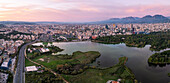 Aerial view of the serene artificial lake surrounded by a beautiful cityscape and mountains at sunset, Tirana, Albania.