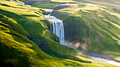 Aerial drone view of Skógafoss waterfall during sunrise in summer time, Southern Iceland.