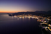 Aerial view of saranda city illuminated at night with a picturesque skyline and tranquil sea, southern albania.