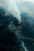 Aerial view of dramatic volcanic landscape with smoke plume and rugged terrain, Grindavik, Iceland.