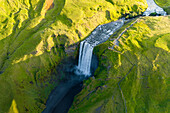 Aerial drone view of Skógafoss waterfall during sunrise in summer time, Southern Iceland.