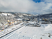 Aerial view of snowy landscape with buildings and trees in a serene valley, Col-des-Roches, Switzerland.