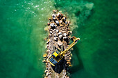 Aerial view of a crane working on the breakwater along the beach in Follonica, Grosseto, Tuscany, Italy.