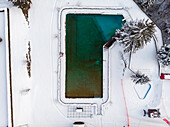 Aerial view of outdoor swimming area covered in snow in winter, Valais, Switzerland.