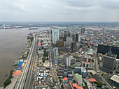Luftaufnahme einer pulsierenden Stadtlandschaft mit modernen Hochhäusern und belebten Straßen in der Nähe des Flusses, Lagos, Nigeria.