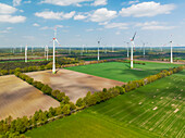 Aerial view of wind turbines, farmland and small forest, Muensterland, Nordrhein-Westfalen, Germany.