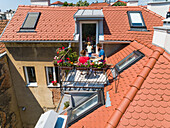 Aerial view of family having breakfast on rooftop balcony in morning sun in Spring.