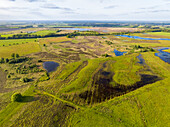 Aerial view of wet grassland, lakes and heather in nature recovery area Scharreveld, Westerbork, Drenthe, Netherlands.