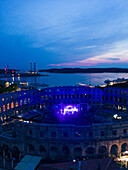 Aerial view of the Pula Amphitheater arena during a concert at sunset, a Roman Amphitheater with underground museum in Pula downtown, Istria, Croatia.