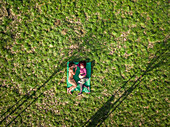 Aerial view of happy young man and pregnant woman lying in grass at park