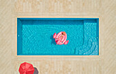 Luftaufnahme eines Mädchens, das auf einem aufblasbaren Flamingo im Pool liegt, Sumarti, Kroatien.