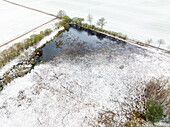 Aerial view of wet field and trees in nature area Witte Veen covered with snow, Twente, Overijssel, Netherlands.