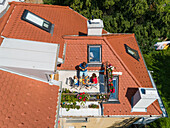 Aerial view of family having breakfast on rooftop balcony in morning sun in Spring.