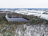 Aerial view of fish pond and mixed forest in autumn with snow, De Witte Bergen, Asten, De Peel, Noord-Brabant, Netherlands.