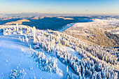 Panoramic aerial view of a snowcovered mountain peak with ski huts, Black Forest, Germany.