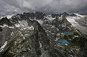 Aerial view of a majestic glacier lake surrounded by rugged snowy mountains under cloudy skies, Gorniy Altay Republic, Russia.