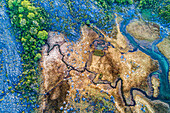 Aerial view of the mineral streamlet flowing in to the lake Lough Gealain, Burren National Park, Ireland. These colours result from the geology of this karst landscape.