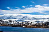 Aerial view of snowy Kolgrafarfjordur fjord with majestic mountains and dramatic clouds, Grundarfjardarbaer, Iceland.