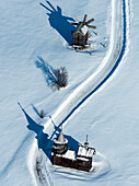 Aerial view of a serene snowy landscape featuring a traditional wooden church and windmill, Karelia Republic, Russia.