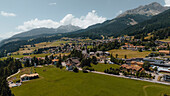 Luftaufnahme der italienischen Alpen mit den Formen der Dolomiten und der Kirche Dolomiti, Pozza di Fassa, Italien.