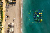 Aerial view of an inflatable beach game along Playa Casablanca beach in Marbella, Andalusia, Spain.