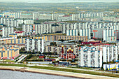 Aerial view of beautiful cityscape with highrise buildings, a river, and a church at sunset, Nizhnevartovsk, Russia.