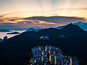 Aerial view of a beautiful cityscape with modern skyscrapers and a stunning sunset over the ocean and mountains, Chung Hom Kok, Hong Kong.