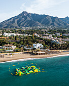 Aerial view of an inflatable beach game along Playa Casablanca beach in Marbella, Andalusia, Spain.