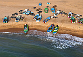 Aerial view of traditional fishing scene with fishermen, fishing nets, and fishing boats on sandy beach, Negombo, Sri Lanka.