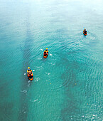 Luftaufnahme einer Drohne mit drei Personen, die in orange-schwarzen Kanus im Indischen Ozean paddeln, Ilot Lievres, Flacq, Mauritius