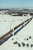 Aerial view of a serene snowy landscape with a modern cable-stayed bridge spanning a frozen river, Murom, Russia.