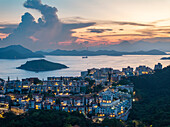 Aerial view of beautiful sunset over the skyline and tranquil bay with modern buildings and distant hills, Chung Hom Kok, Hong Kong.