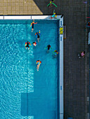 Aerial view of public pools with people swimming under the sunny daylight, Wedding, Berlin, Germany.