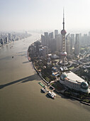 Luftaufnahme der Skyline von Shanghai mit dem Oriental Pearl Tower im Vordergrund und dem vorbeifließenden Huangpu-Fluss, China.