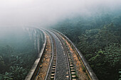Aerial view of famous Nine arch railway bridge going through green jungle landscape in morning mist cloud, Ella, Sri Lanka.