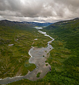 Luftaufnahme des Sees Vuolimus Gorsajavri mit einem gewundenen Fluss und majestätischen Bergen, Abisko-Nationalpark, Schweden.
