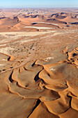 Luftaufnahme von Sanddünen und Kameldornbäumen (Acacia erioloba) in einem trockenen Flussbett in der Namib-Wüste. Luftaufnahme. Namib-Naukluft-Nationalpark, Namibia.