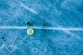 Aerial view of a person staying in a technical yellow winter tent over the frozen river estuary in Kauno Mariu national park near Kaunas, Lithuania.