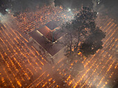 Aerial view of a vibrant night festival with a sacred temple surrounded by a crowd and lit candles, Baradi, Sonargaon, Bangladesh.