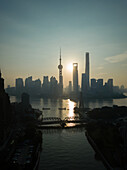 Luftaufnahme der Skyline von Shanghai bei Sonnenuntergang mit vorbeifließendem Huangpu-Fluss, China.
