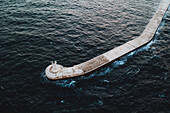 Aerial view of pier and lighthouse in dark water near Valletta, Malta island.
