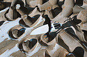 Aerial view of surfer holding surfboard and standing near concrete wave breakers in Smiltyne beach, Klaipeda, Lithuania.