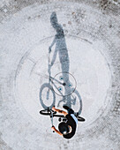 Aerial view of BMX bike rider silhouette shadow standing on concrete surface in Panevezys, Lithuania.