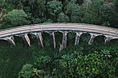 Aerial view of tourists walking on famous Nine arch railway bridge going through green jungle landscape in Demodara, Ella, Sri Lanka.