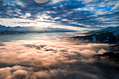 Luftaufnahme eines bewölkten Tals mit Sonnenuntergang in den Alpen bei Piesendorf, Kaprun, Österreich im Winter.