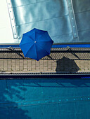 Luftaufnahme eines öffentlichen Schwimmbads mit blauem Wasser und Sonnenschirmen an einem Sommertag, Mitte, Deutschland.