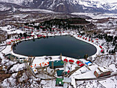 Aerial view of snowy mountains, lake, and village in Skardu, Punjab, Pakistan.