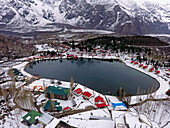 Aerial view of snowy mountains, lake, and village, Skardu, Punjab, Pakistan.